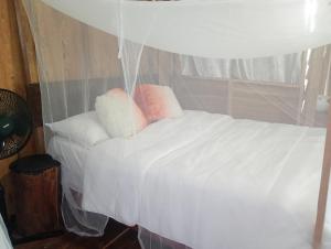 a bedroom with a white bed with two pillows at su cabaña Río Celeste in Rio Celeste