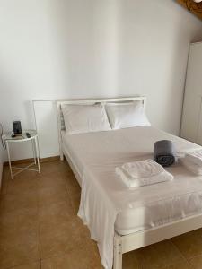 a bedroom with a bed with white sheets and a table at Evelyn House in Samos