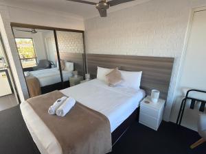 a bedroom with a large bed with towels on it at Bribie Waterways Motel in Bongaree