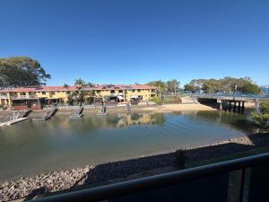 a view of a river with benches and a bridge at Bribie Waterways Motel in Bongaree