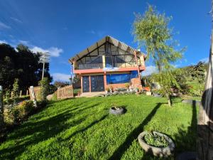 a house on a grassy yard with a tree at Rinconcito campesino in Aquitania
