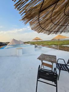 a table and chairs and straw umbrellas on a patio at COMPORTA SIDE - Tents in Setúbal