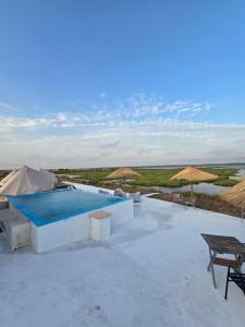 a resort with a swimming pool and tables and umbrellas at COMPORTA SIDE - Tents in Setúbal