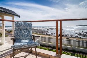 ein blauer Stuhl auf einem Balkon mit Meerblick in der Unterkunft Geheim Luxury Seafront in Hermanus