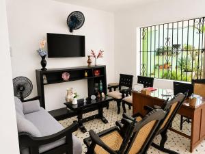 a living room with chairs and a table and a tv at Casa Hotel La Unión in Santa Cruz de Mompox