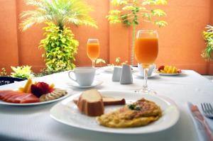 a table with a plate of food and two glasses of orange juice at Hotel Mare Apartasuite in Cali