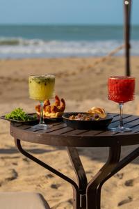 a table with two drinks and food on the beach at Vila Torém in Icaraí