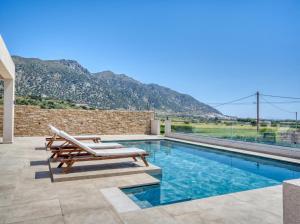 a swimming pool with chairs and a mountain in the background at Villa Dioni in Kardamaina