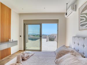 a bedroom with a bed and a sliding glass door at Villa Dioni in Kardamaina +19 photos