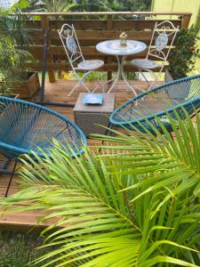 a patio with chairs and a table and a palm plant at L'Isménia, L'écrin Zen in Le Gosier +3 photos