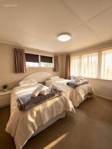 two beds in a room with windows at Cosy on Goldfinch in Ohakune