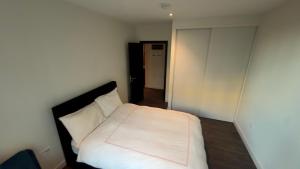 a bedroom with a bed with white sheets and a door at Greenford Quay in Harrow on the Hill