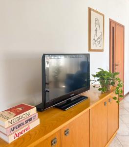 a flat screen tv sitting on top of a wooden cabinet at Lido di Camaiore-Spacious & Bright 2Bedrooms House in Lido di Camaiore