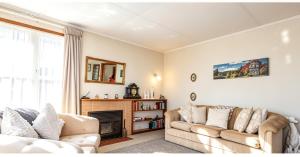 a living room with two couches and a fireplace at Cosy on Goldfinch in Ohakune