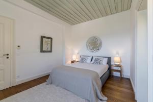 a white bedroom with a bed and two lamps at Villa Avola Bol Exclusive Beach Access in Bol