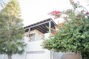 a white building with flowering trees in front of it at Siroa Serene in Rózia