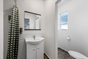 a white bathroom with a sink and a mirror at Bings Motel in Blenheim +24 photos