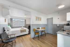 a bedroom with a bed and a table and a kitchen at Bings Motel in Blenheim
