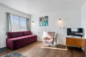 a living room with a purple couch and a tv at Bings Motel in Blenheim