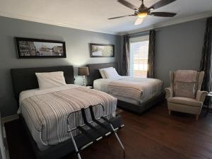 a bedroom with two beds and a chair and a ceiling fan at Casa Blanca Boutique Bed & Breakfast in Niagara-on-the-Lake