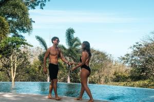 a man and a woman in bathing suits standing by a pool at Mikado Natural Lodge in Playa Avellana