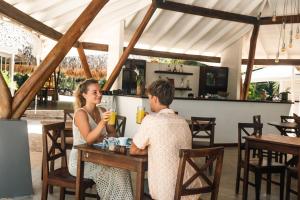 a man and woman sitting at a table in a restaurant at Mikado Natural Lodge in Playa Avellana
