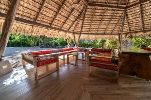 a patio with tables and chairs under a straw roof at Mikado Natural Lodge in Playa Avellana