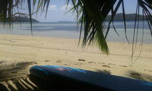 a blue surfboard sitting on a beach with the ocean at Chalets Anse Possession in Baie Sainte Anne
