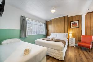 a hotel room with two beds and a red chair at Bings Motel in Blenheim