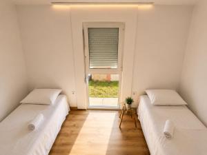two twin beds in a room with a window at Blue Yard in Lepetani