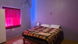 a bedroom with a bed with purple walls and a window at Pisac cosmic in Pisac