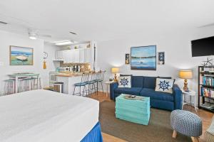 a bedroom with a blue couch and a kitchen at Coastal Condo with heated pool hot tub tennis & beach access in Destin