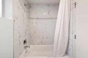 a white bathroom with a tub and a shower curtain at DTPH Cozy Corner - Pool & Parking in Phoenix