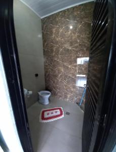 a bathroom with a toilet and a red rug at Refúgio Serenna in Bebedouro