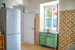 a kitchen with a refrigerator and a green cabinet at Casa do Arco da Vila in Faro