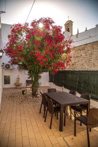 a table and chairs and a tree with red flowers at Casa do Arco da Vila in Faro
