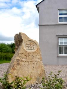 a rock in front of a white building at Carland Cottage in Carland