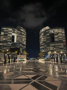 two tall buildings in a parking lot at night at The Gate 05 New Alamein in El Alamein