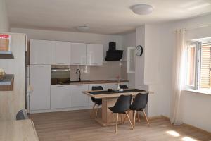 a kitchen with white cabinets and a table and chairs at Apartments and rooms by the sea Nevidjane, Pasman - 11902 in Neviđane +30 photos