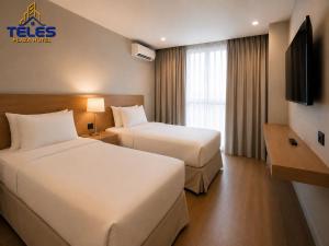 a hotel room with two beds and a television at Teles Plaza Hotel in Macacos