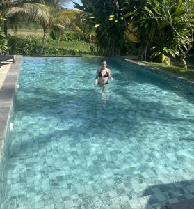 a woman standing in the water in a swimming pool at Kingfisher Beach Resort-Yala Safari in Kirinda