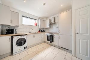 a kitchen with white cabinets and a washer and dryer at St John's Flats, Newsome in Huddersfield