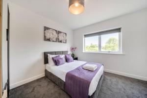 a bedroom with a bed with purple pillows and a window at St John's Flats, Newsome in Huddersfield