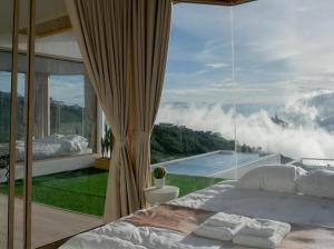 a bedroom with a bed and a large window at รีทรีท ภูทับเบิก in Ban Maeo Thap Boek