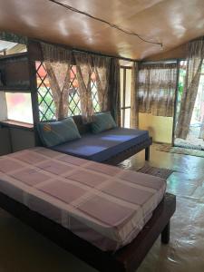 a large bed in a room with windows at FARE Tatahi in Parea