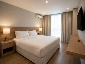 a bedroom with a large white bed and a window at Teles Plaza Hotel in Macacos