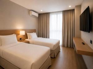 a hotel room with two beds and a television at Teles Plaza Hotel in Macacos