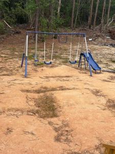 an empty playground with swings in a dirt field at The Relaxation Haven in McRae