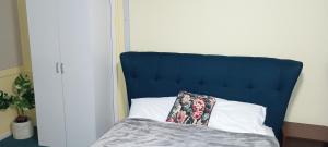 a bed with a blue head board with a pillow at Cooma Center Cortina Studio in Cooma