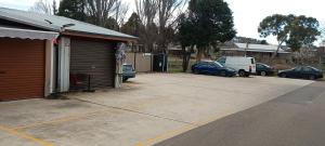 a parking lot next to a garage with cars parked at Cooma Center Cortina Studio in Cooma